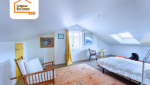 Chambre sous combles aménagée à Thyez 74300 avec mobilier bois, murs blancs, lumière naturelle et Velux – rénovation intérieure en Haute-Savoie.