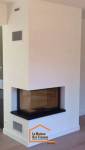 Cheminée encastrée d’angle à foyer fermé avec finition contemporaine blanche – installation réalisée en Haute-Savoie.