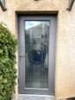 Rénovation d'une porte d'entrée, dans un style Art Déco, maison située à Ecully (69130) : porte en aluminium, double vitrage, coloris gris texturé