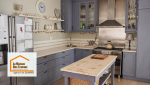 Cuisine rénovée au style campagne chic avec meubles bleu-gris, crédence claire et îlot central en bois patiné – un projet réalisé par La Maison Des Travaux Quimper.