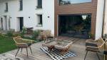Aménagement extérieur finalisé avec terrasse bois sur-mesure devant une maison en pisé à La Côte-Saint-André : un véritable espace de vie convivial et chaleureux