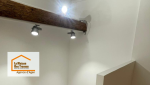 Jeu de lumière et charme de l’ancien : mise en valeur des poutres et installation de luminaires modernes pour une ambiance douce sous les toits.