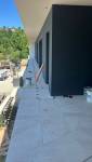 Pose d’un carrelage extérieur grand format pour la création d’une terrasse contemporaine autour d’une maison à Voiron.