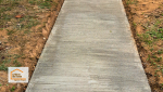 Finition striée du béton pour un effet antidérapant, garantissant sécurité et durabilité du chemin extérieur.