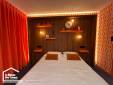 Vue d'ensemble d'une chambre parentale rénovée avec tête de lit en bois et rideaux orange.