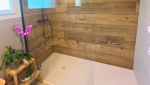 Détail de la douche moderne avec paroi vitrée et robinetterie noire.