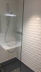 Douche rénovée avec carrelage métro blanc et colonne de douche moderne.