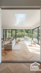 Vue intérieure d'une extension de maison avec grandes baies vitrées, parquet clair et décoration moderne.
