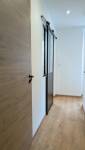Couloir rénové à Voiron avec revêtement de sol effet bois, portes contemporaines et verrière coulissante.