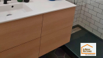 Meuble vasque suspendu en finition bois clair avec miroir rond et éclairage design dans une salle de bain contemporaine rénovée près du Tholonet.