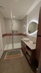Salle de bain entièrement rénovée à Voiron avec grande douche vitrée, meuble vasque et miroir rétroéclairé.