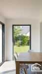Intérieur lumineux d'une extension avec toit plat, montrant un plafond lisse et une vue dégagée sur le jardin.