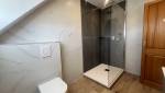 Nouvelle salle de bain avec douche vitrée, WC suspendu et revêtements contemporains.