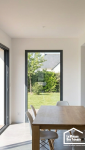 Intérieur lumineux d'une extension avec toit plat, montrant un plafond lisse et une vue dégagée sur le jardin.