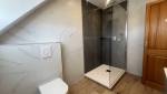 Nouvelle salle de bain avec douche vitrée, WC suspendu et revêtements contemporains.