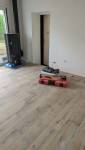 Pose d’un nouveau revêtement de sol effet bois dans la pièce de vie d’une maison en rénovation à Voiron.