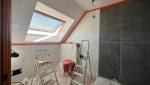 Travaux de salle de bain en cours avec carrelage effet marbre, mur foncé, WC suspendu protégé et échelles de chantier.