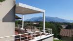 Vue extérieure de la pergola bioclimatique blanche, intégrée à la façade et aux garde-corps de la résidence.