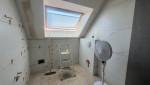 Salle de bain sous pente en cours de rénovation avec carrelage grand format effet marbre et fenêtre de toit.