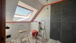 Travaux de salle de bain en cours avec carrelage effet marbre, mur foncé, WC suspendu protégé et échelles de chantier.