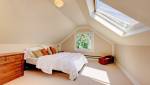 Chambre aménagée sous les combles avec lumière naturelle et toiture mansardée