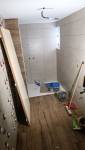 Chantier de rénovation complète d’une salle de bain ancienne à Charancieu avec pose du carrelage mural et du sol.