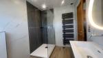 Vue finale de la salle de bain rénovée avec douche vitrée et sèche-serviettes design.