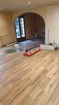 Chantier de pose du carrelage imitation bois dans le salon d’une maison à Renage.