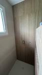 Pose du carrelage effet bois dans l'espace douche pour une ambiance naturelle et contemporaine.