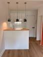 Cuisine ouverte avec bar et pièce de vie terracotta, rénovation studio Paris 19