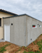 Murs du garage en modules béton avant enduit, avec porte latérale et deux fenêtres.