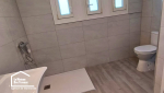 Aménagement d’une salle d’eau accessible à Castillonnès avec douche sans ressaut, robinetterie murale et lavabo suspendu.
