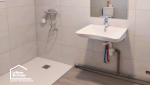Salle de bain PMR rénovée à Castillonnès avec douche de plain-pied, lavabo suspendu et espace dégagé pour faciliter les déplacements.
