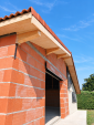 Résultat des travaux de charpente et de couverture à Labège, en Haute-Garonne, avec des débords de toiture en bois apparent.
