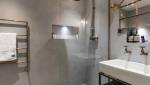 ambiance industrielle avec sèche serviette en tuyaux de cuivre et mur en béton brut