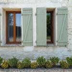 Volets PVC finition vert tilleul sur encadrement fenêtre finition bois chaud