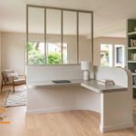 Une bibliothèque intégrée et un bureau d'angle sur-mesure, conçus en béton cellulaire, délimitent astucieusement un espace de télétravail dans ce salon baigné de lumière