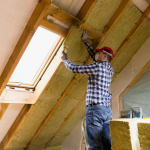Travaux de rénovation énergétique avec isolation des combles sous toiture et pose d’isolant thermique autour d’une fenêtre de toit