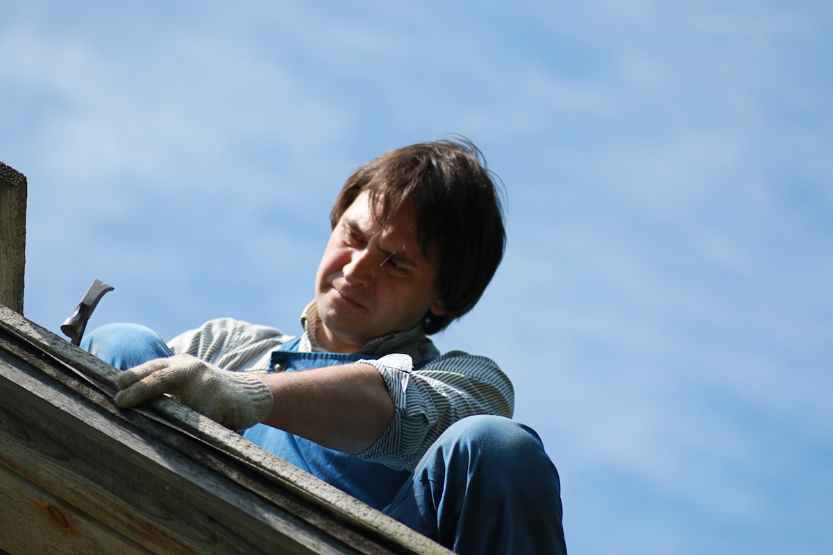 Un charpentier-couvreur travaille sur le toit d'une maison